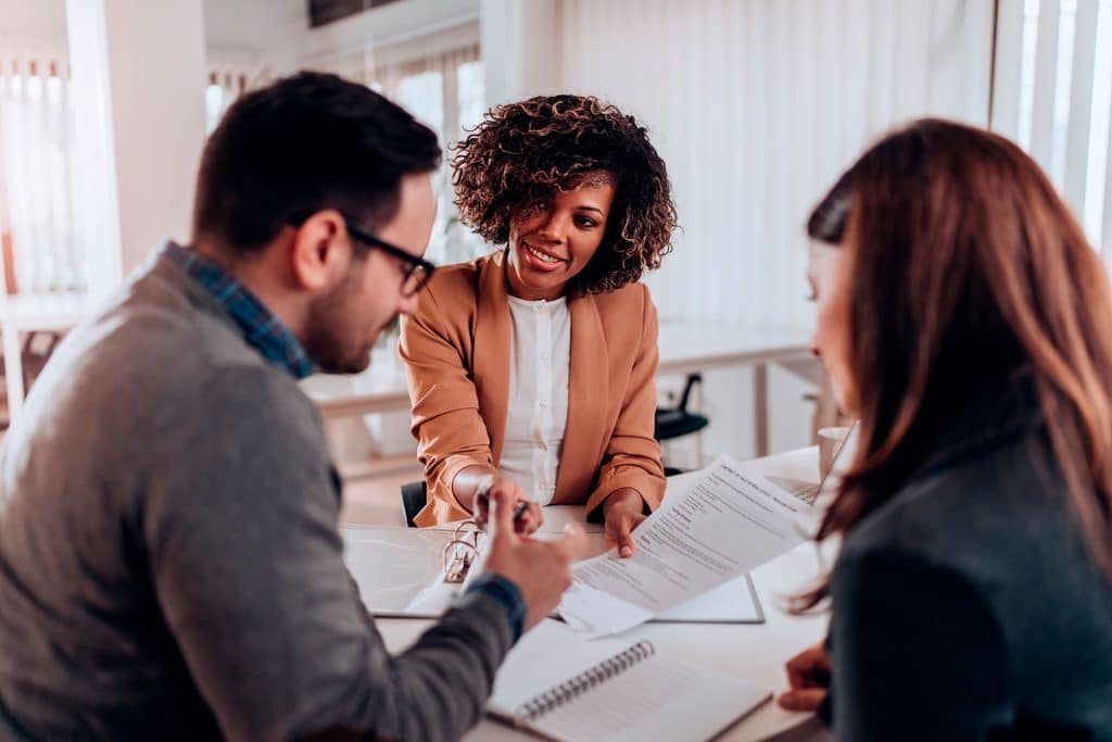 Two woman and a man sitting by the table and talking loans.